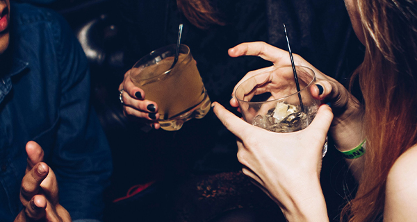 People holding alcoholic drinks with straws