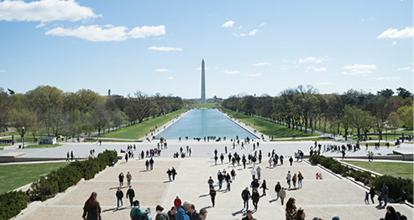 A wideangle shot of a park with a body of water through the middle and tall tower in the middle of the frame