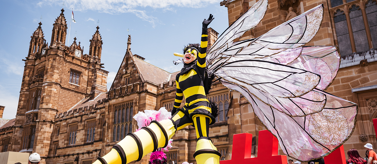 A performer in a bee costume in front of the quad