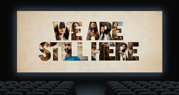 A movie theater screen displays the words 'We Are Still Here' 