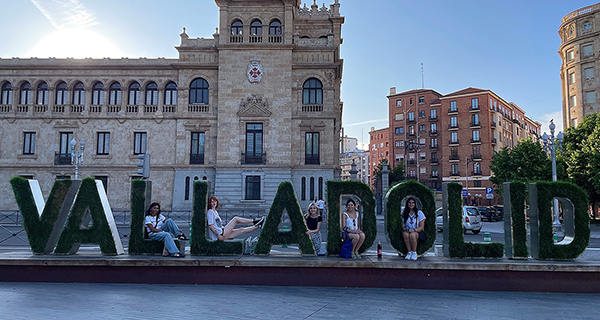 Students sitting on giant letters in city spelling VALLADOLID