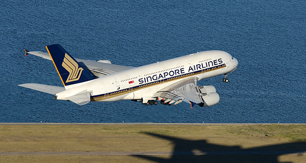 Singapore Airlines plane taking off with a body of water in the background