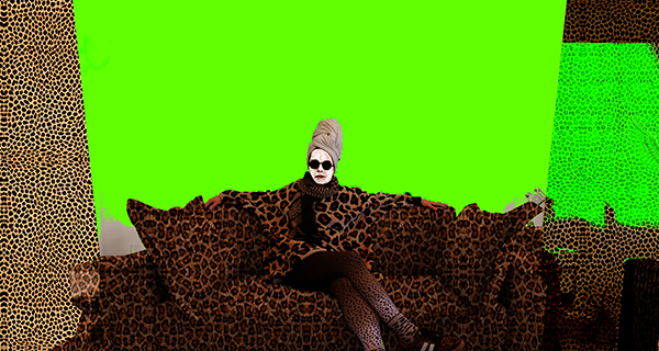 A person in sunglasses sits confidently on a leopard-print sofa against a vivid green backdrop.