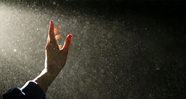 A hand in the air surrounded by dust particles floating in the air, creating a serene and hopeful atmosphere.