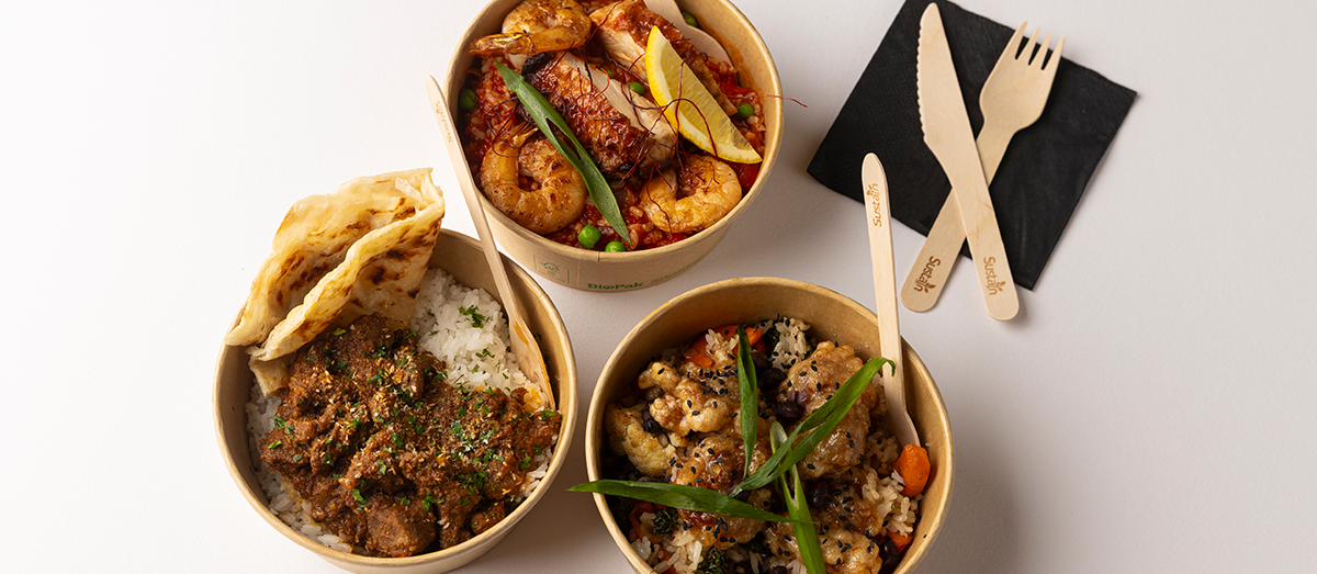 Three bowls of food with pita bread and wooden utensils