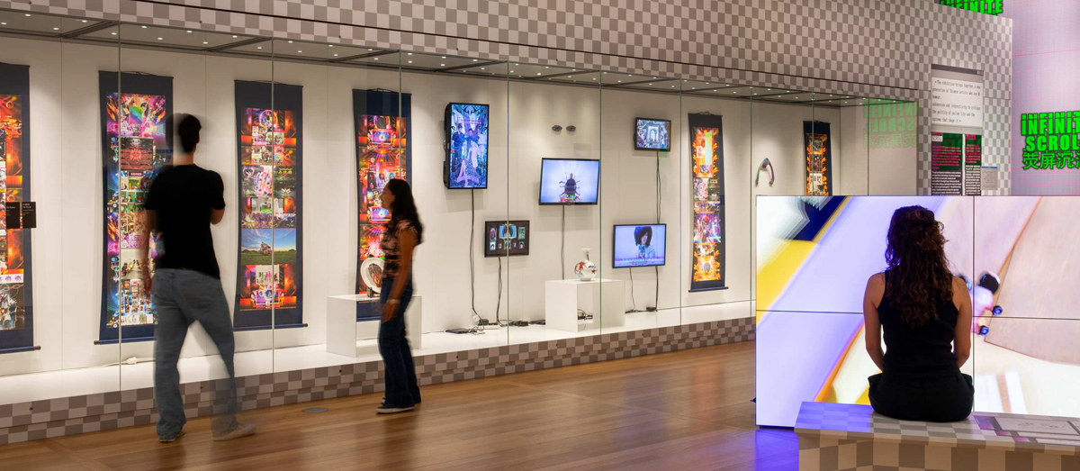 Museum exhibit features colourful digital art displays on walls, with visitors exploring.