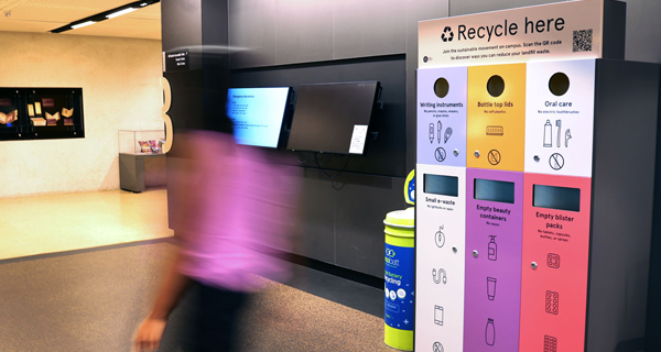 A student walking past the recycling hub at FIsher Library