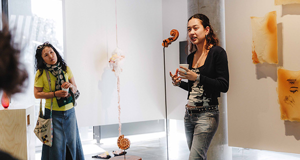 SCA student Lily Tucker with work VITULA_SUITE (2025), giving an artist talk at the USU Creative Awards 2025. Photography by Michael Cole, courtesy of USU.