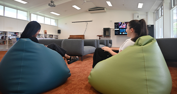 Two students sitting on beanbags in a large, bright room