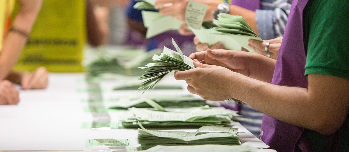 People counting many green ballot papers