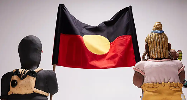 Stolen Land sculpture by Billy Bain featuring two people holding the Aboriginal flag.