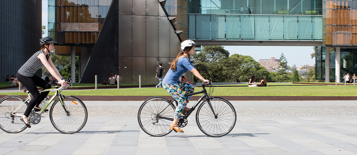 Two students riding bikes in a pedestrianised area