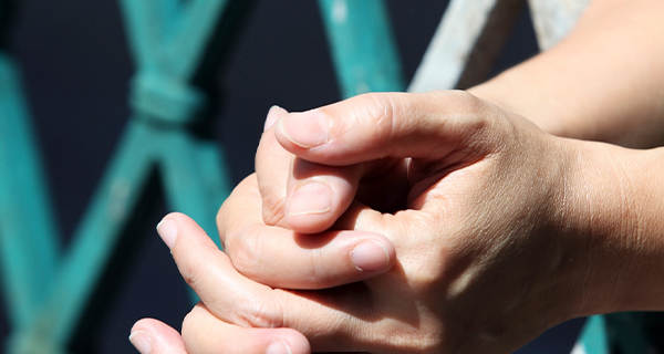 Close-range shot of hands outside cell bars