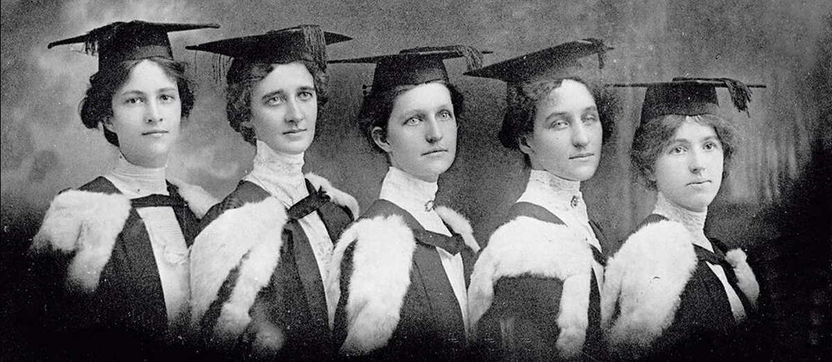 A black and white photo of female students wearing graduate caps and gowns