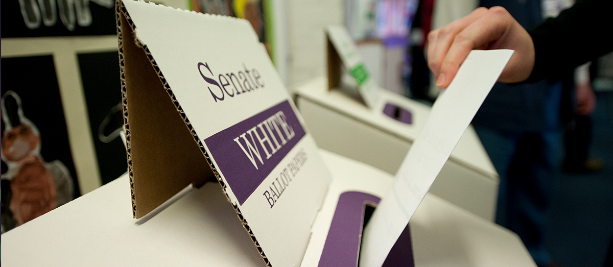 A senate ballot box with someone putting their vote in it.