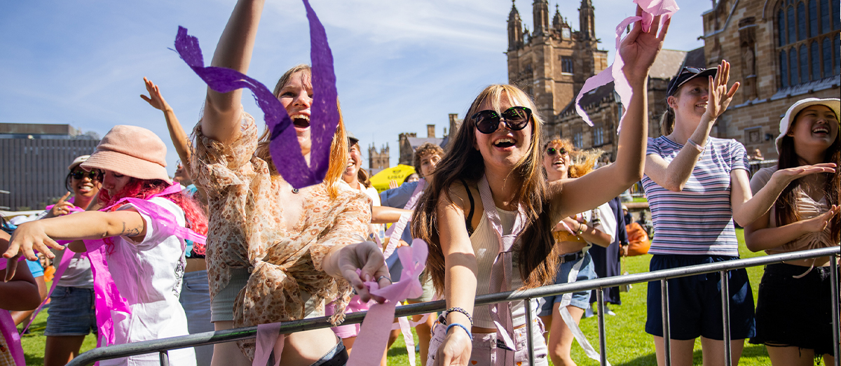 Two students dancing with colourful streamers coming down