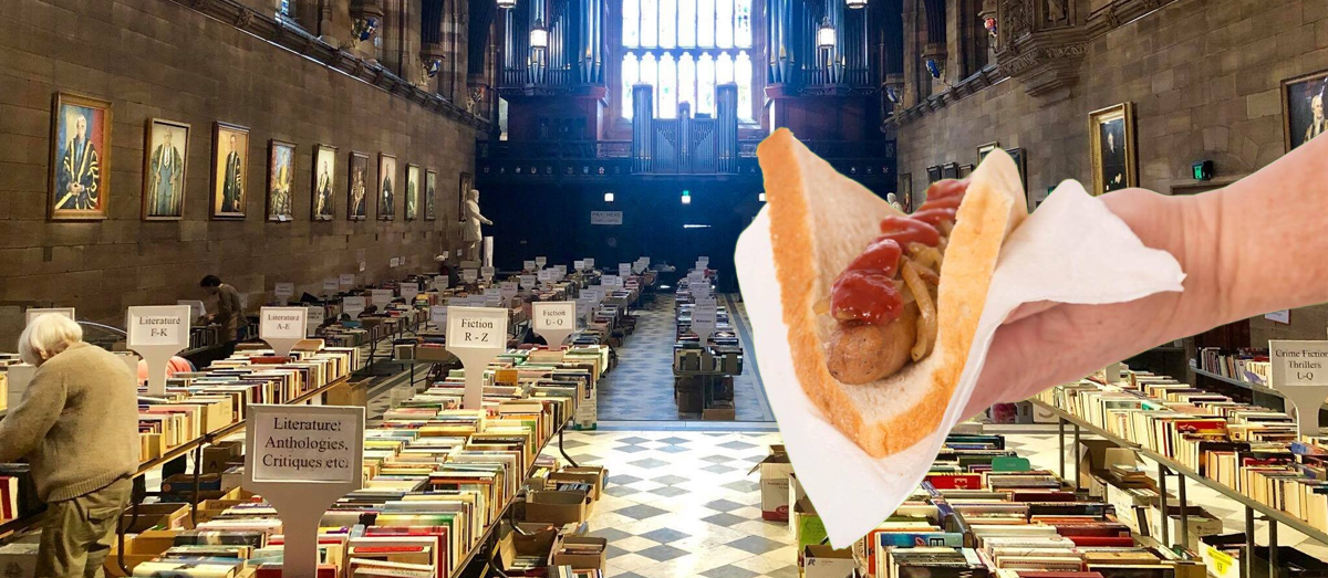 The Great Hall Book Fair with a hand holding a sausage sandwich superimposed.