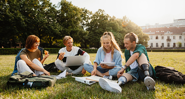 Students sitting on grass outdoors in campus area