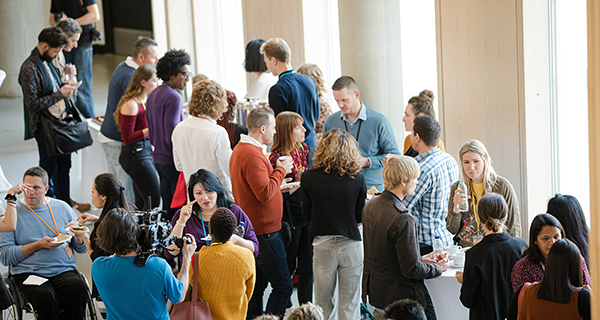 A group of people engage in lively conversation and networking at an indoor event