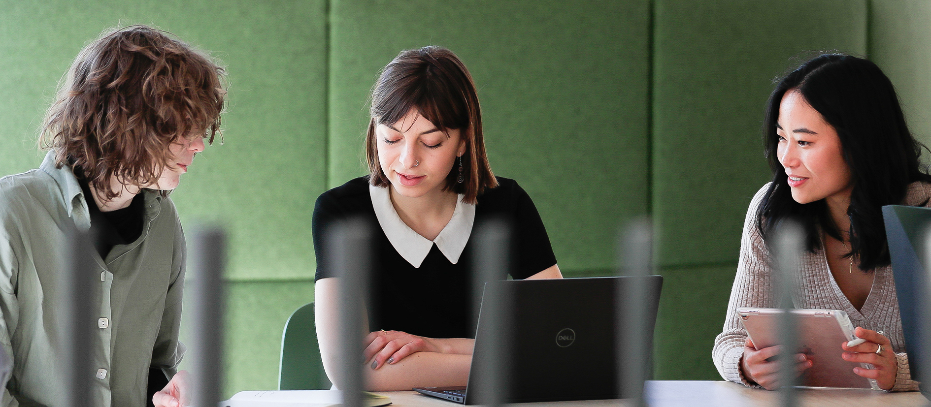 Three female students looking down at a paper on a desk