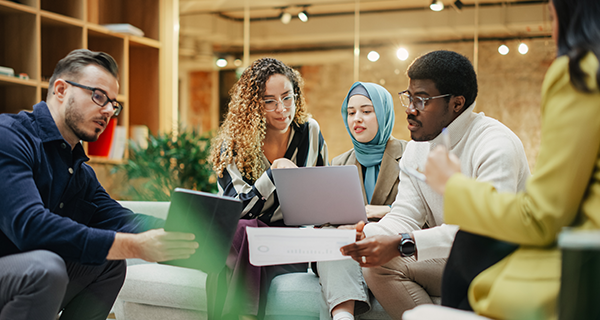Five people sitting on a couch comparing notes.