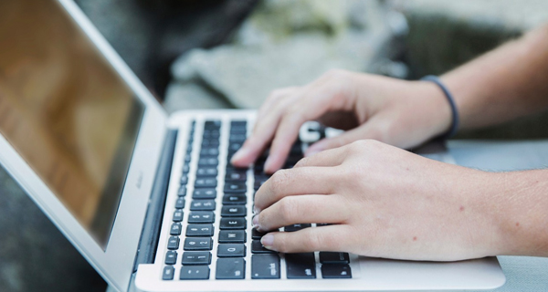 A graphic of hands on a laptop