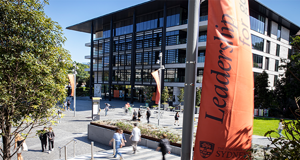 Students walking down Eastern avenue. There is a flag that reads 'Leadership for good'.