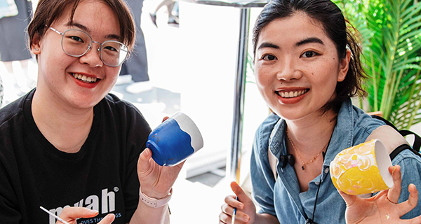 Two students painting their pot plants
