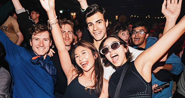 People smiling with hands in the air at Manning Bar