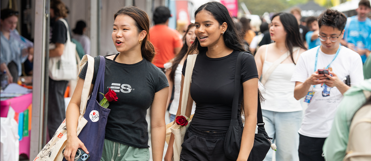 Students walking down Eastern Avenue on Welcome Week browsing stalls