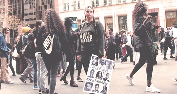 An individual standing with a poster in hand amidst a crowd at a Black Lives Matter rally, Sydney (2015). Photo: Barbara McGrady.
